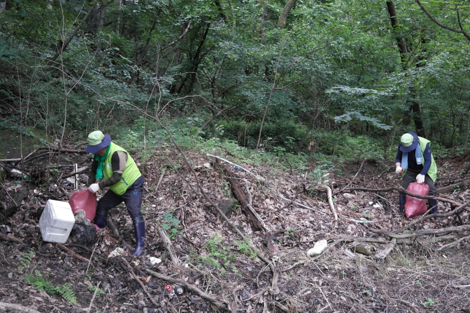 옥천군자연보호협의회가 대청호 주변 풀숲에 널브러져 있는 쓰레기를 줍고 있다.