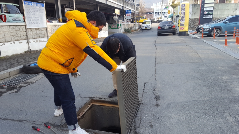 보건소 담당자들이 맨홀안에 유충구제제를 투약하고 있다.