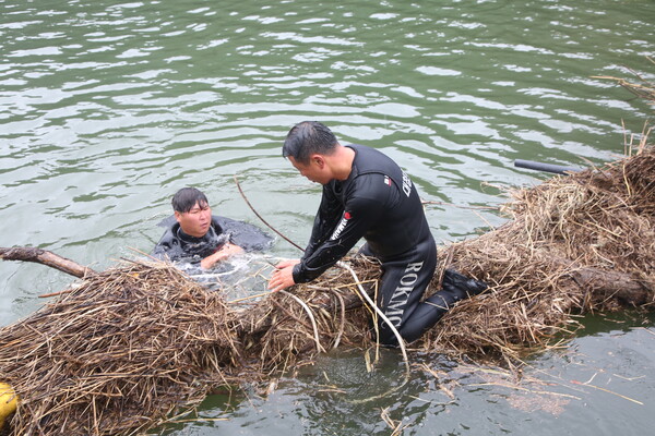 노희철 구조팀장(왼쪽)과 김태원 대장이 폐목재 수거를 위해 물 속에서 작업을 하고 있다.