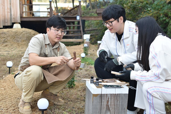 우지후 공방장이 목공 체험을 하러 대전에서 온 청년들에게 나무 수저를 깎는 방법을 알려주고 있다.