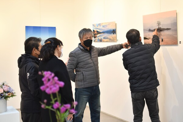 나인포토 안치성(오른쪽에서 두 번째) 회장이 관람객들에게 전시 작품에 관해 설명하고 있다.