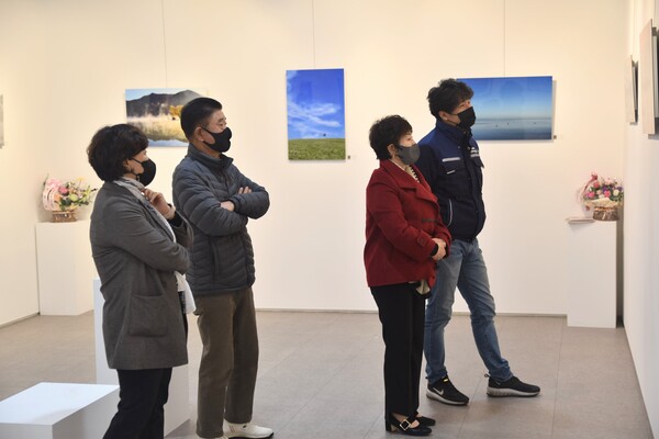 이번 전시에 참여한 나인포토 회원들과 관람객들이 작품을 보고 있다.