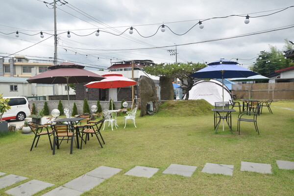 담아정 카페 마당에 야외 테이블과 파라솔, 텐트가 있다. 캠핑 공간으로 활용할 수 있다.