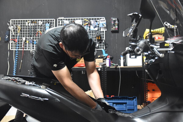 J모터스 조 훈 대표가 실내 작업장에서 오토바이 수리를 하고 있다.