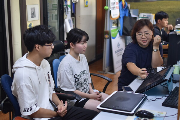 예인기획 김 윤(오른쪽) 대표가 옥천고 1학년 김재환(왼쪽), 이예서(가운데) 학생에게 만화 그릴 때 사용하는 기기와 프로그램을 보여주고 있다. 