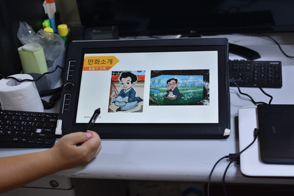 김 윤 대표가 지역 인물인 정순철 선생과 정지용 시인을 캐릭터화해서 그린 그림을 보여주고 있다.