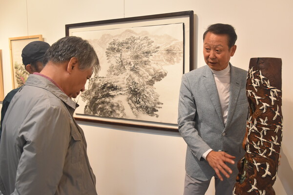 현산 강민(오른쪽) 작가가 대추나무로 만든 '백학도'를 소개하고 있다.