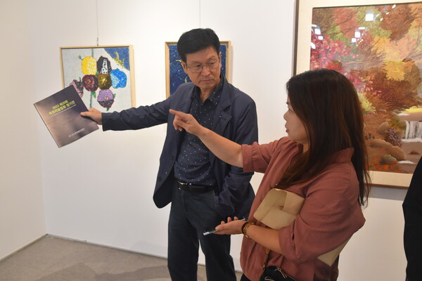 조정미(오른쪽) 작가가 한국미술협회 영동지부 이강혁(왼쪽) 지부장에게 수채화로 그림 설명을 하고 있다.