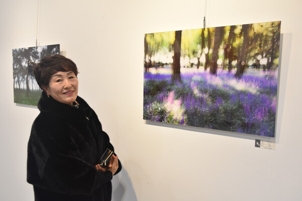 신혜정 씨가 충남 서천에 소나무숲과 맥문동 꽃밭을 배경으로 한 '보랏빛 향기' 앞에서 기념촬영을 하고 있다.